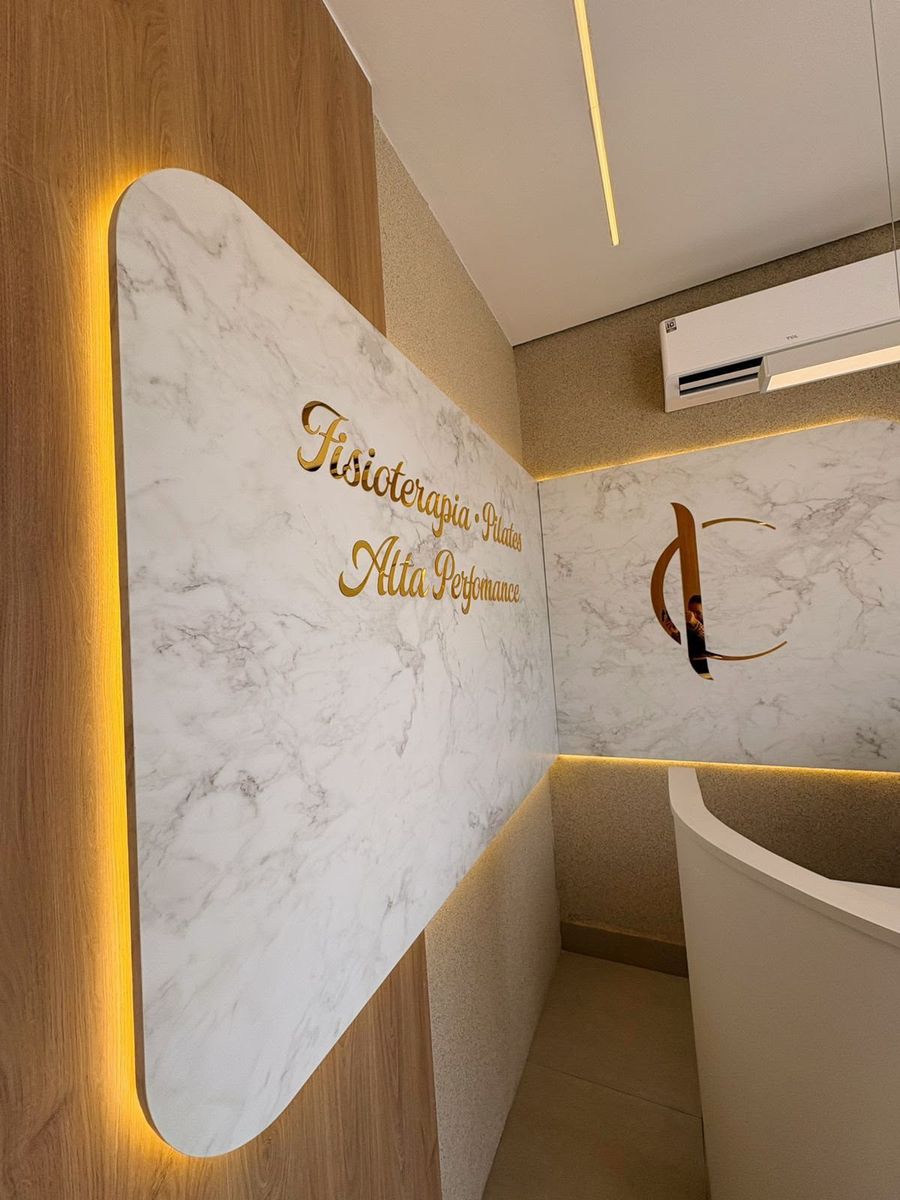 Painel de mármore iluminado na recepção com os dizeres Fisioterapia, Pilates, Alta Performance